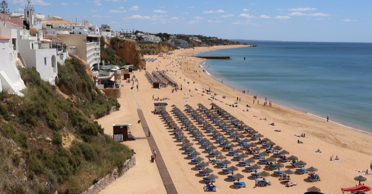 View over Albufeira’s town beach with rows of parasols, cliffs and the whitewashed houses of the old town